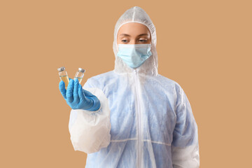 Medical worker in protective suit and with ampules on beige background. Vaccination concept