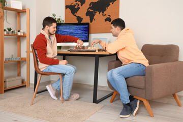 Fototapeta premium Handsome young brothers playing chess in room