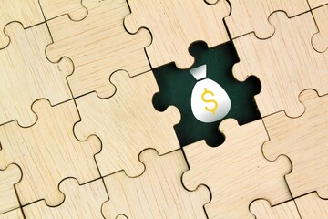 wooden puzzle with one puzzle missing and a money icon inside. the concept of finding...