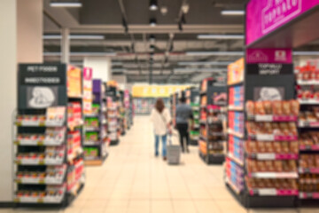 Supermarket aisle with shoppers. Abstract blur as background.