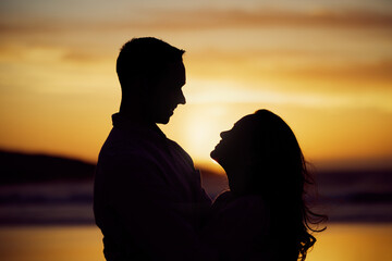 Sunset, silhouette or couple on beach for hug, love or romance on honeymoon. Man, woman or travel in nature with embrace, trust or commitment in relationship on holiday for milestone or celebration