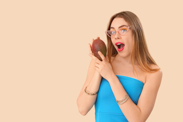 Shocked young woman with sweet mango fruit on beige background