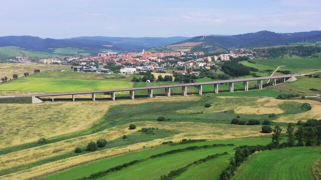 Drone shot of European route E50 highway road through green agricultural fields landscape connecting European continent, Levoca town in background