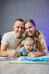 Young happy family mom dad and little son playing at home in the living room. Family relationships.