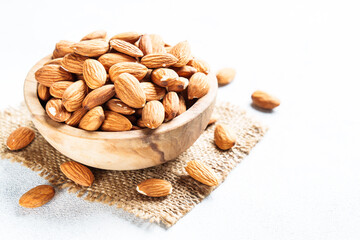 Almond nuts in wooden bowl at white background. Close up.