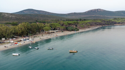 Aerial view of Mugoni beach near Alghero in Sardinia island, with people sunbathing, some boats anchored and calm sea