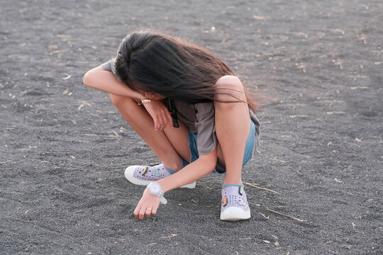 Little girl playing sands on the beach under hot steaming sun
