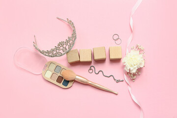Wooden cubes with prom tiara, eyeshadows and accessories on pink background © Pixel-Shot