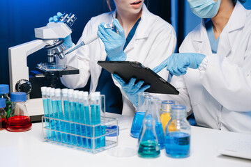 Fototapeta premium Young scientists conducting research investigations in a medical laboratory, a researcher in the foreground is using a microscope in laboratory