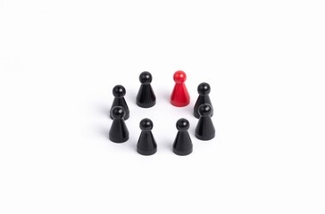 inclusion, integration: several black and one red playing piece are standing in a circle on a white...