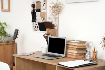Laptop with books on table in teenager's room