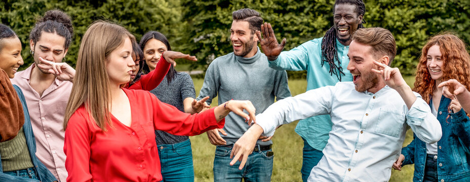 Diverse group of young friends having fun outdoors, laughing and joking in park, multicultural people enjoying social gathering
