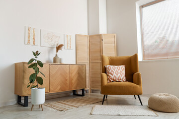 Interior of stylish living room with paintings, commode and armchair