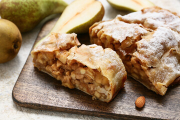 Wooden board with pieces of tasty pear strudel, closeup