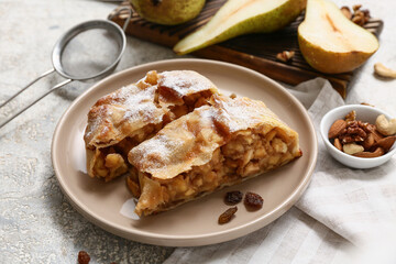 Plate with pieces of tasty pear strudel and ingredients on grey grunge background