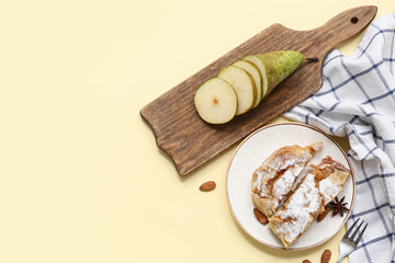 Plate with pieces of tasty pear strudel and cut fresh fruit on yellow background