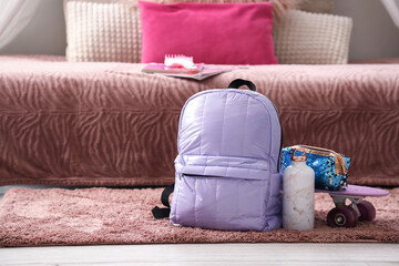 Backpack with water bottle, pencil case and skateboard in children's bedroom