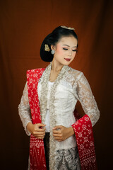 A young Indonesian woman with a happy expression wearing a white kebaya. Kartini's Day Concept.