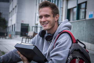 teenage student with books and headphones outside the university