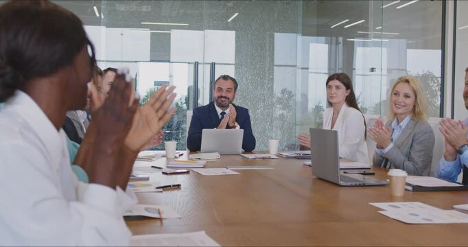 Corporate business team meeting in a boardroom and celebrating success and development. Group of diverse people sitting together at a big table and applauding