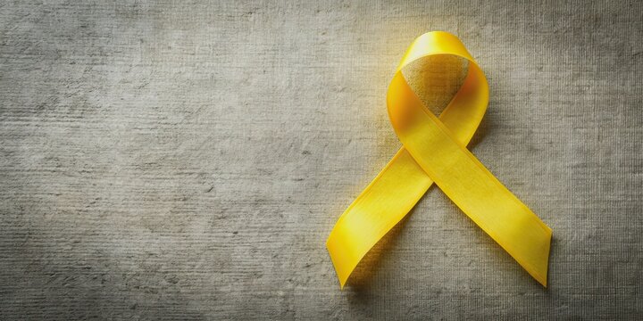 Vibrant yellow ribbon isolated on soft, textured background with ample copy space, perfect for promoting endometriosis awareness, microencephaly support, and suicide prevention.