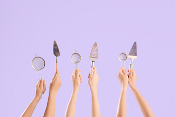 Female hands with spatulas and sieves on purple background