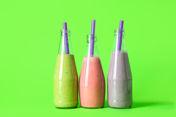 Bottles of different fresh smoothie on green background