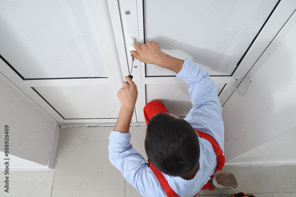 Wall mural male worker with screwdriver repairing door in office