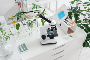 Microscope and test tubes with plants on shelf in Biology classroom