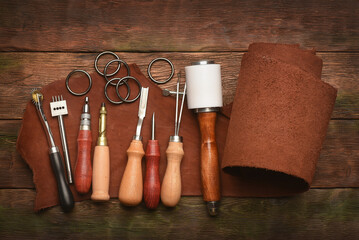 Leather craft work tools and leather on the tanner workbench concept background.