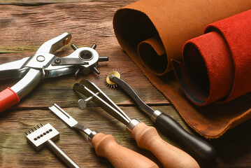 Leather craft work tools and leather on the tanner workbench concept background.