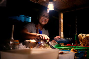 Woman selling "Angkringan" street food on the road side of Yogyakarta