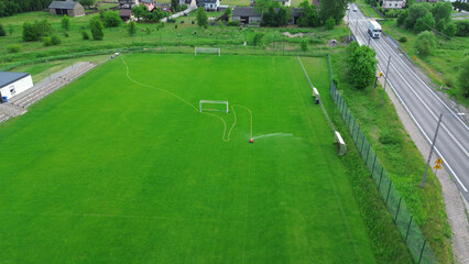 Soccer field with automatic sprinklers on a sunny day