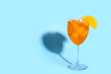 Glass of Aperol spritz cocktail on blue background