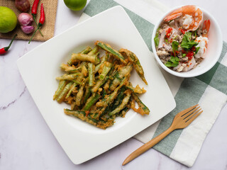 Deep fried morning glory with spicy salad - Thai food called Yum Puk Boong Krob at top view on marble table