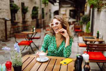 Beautiful woman with cup of coffee in street cafe. People, fashion, lifestyle, travel and vacations. Food and drink.
