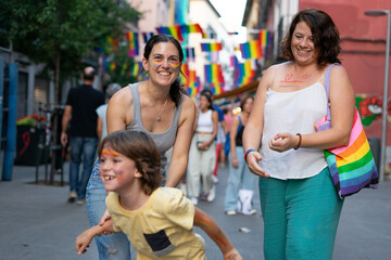Family of two lesbian mothers and their son walking through the city on LGBT pride day
