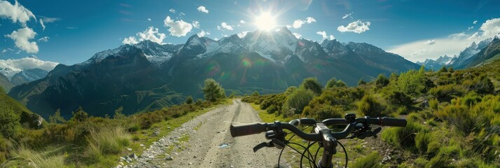 Mountain landscape scenery features a black bicycle parked on the left side of the frame facing right towards majestic snow-capped peaks rising against a clear blue sky dotted with fluffy clouds.