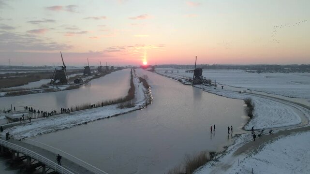 Aerial view of frozen river with windmills, snow, and ice, Kinderdijk, Netherlands.