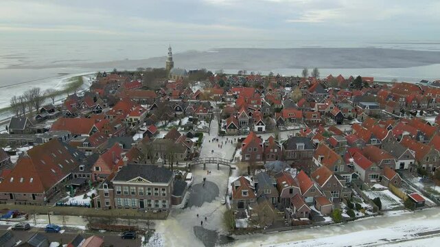 Aerial view of snowy village with charming rooftops and frozen water, Hindeloopen, Friesland, Netherlands.