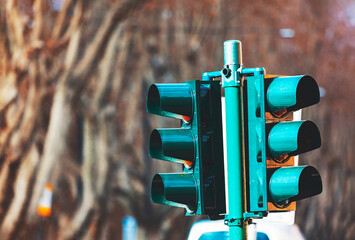 Traffic light is on a pole in the city. Traffic signal is mounted on a post in the urban area