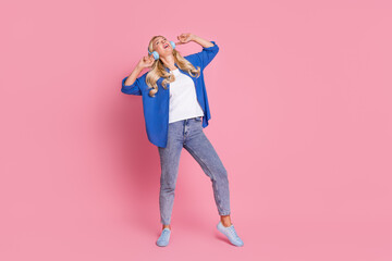 Full size photo of nice woman with wavy hair dressed blue shirt dancing in headphones enjoy pop playlist isolated on pink color background