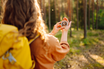 Hands of woman holding navigational compass. Female traveler holding compass in hands and navigating in nature. The concept of hiking, nature.