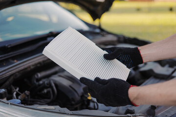 Auto mechanic holds a new car cabin air filter to replace the old filter.