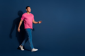 Full body photo of young funny guy wearing casual pink t shirt and jeans strolling in his brand new...