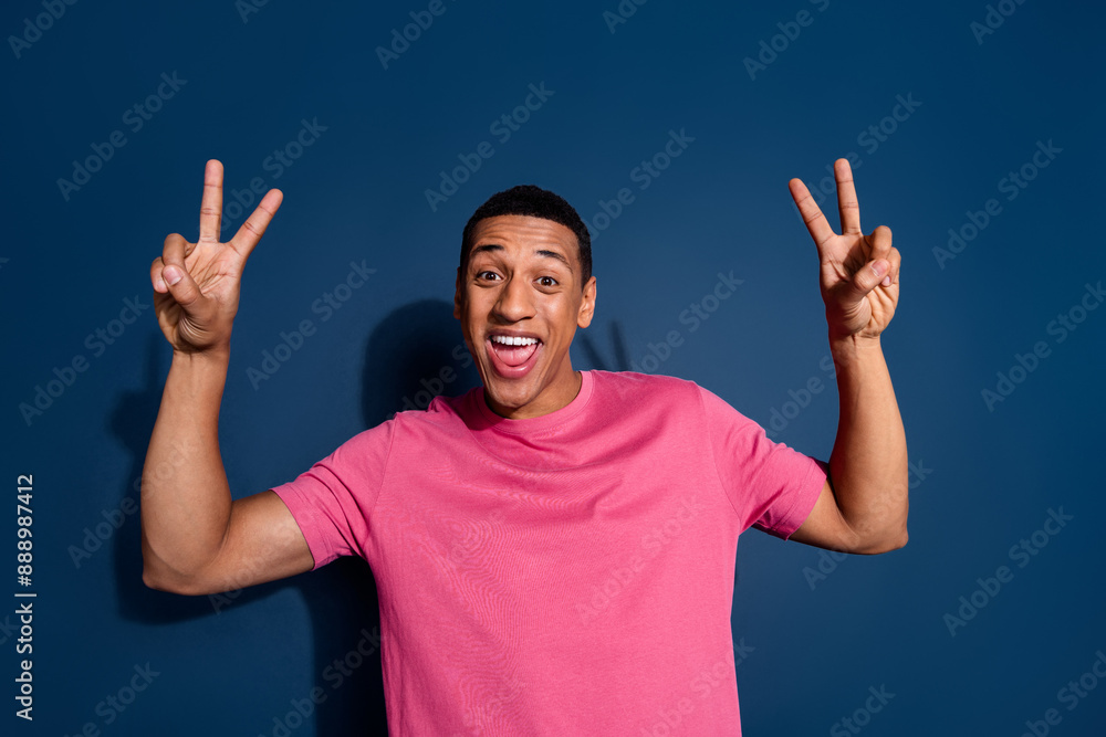 Sticker Photo of stylish wearing pink t shirt young handsome guy with short haircut smiling showing double v sign isolated on dark blue color background