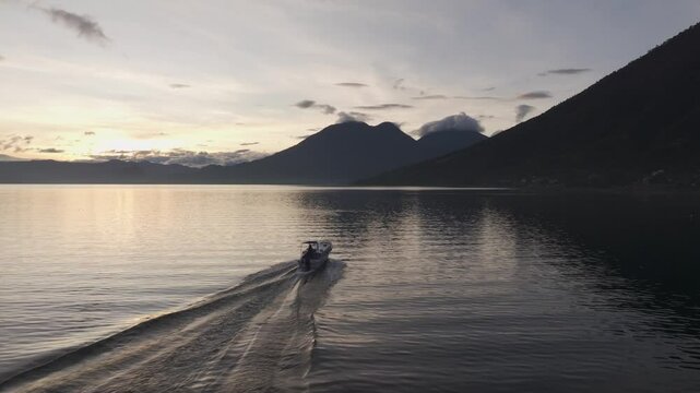 Aerial view of Lake Atitlan at sunrise with boat, city, and volcano, Solola Department, Guatemala.