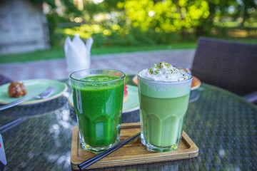 Two drinks on a table, one is green and the other is white