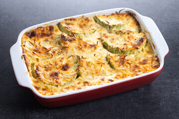 Casserole with cheese and gratin zucchini on black stone background