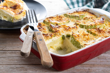 Casserole with cheese and gratin zucchini on wooden table